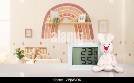 Digitales Hygrometer mit Thermometer auf dem Tisch im Kinderzimmer. Optimale Luftfeuchtigkeit für Kinder Stockfoto