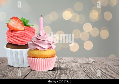 Süße Geburtstagskuchen auf Holztisch gegen verschwommenes Licht. Platz für Text Stockfoto