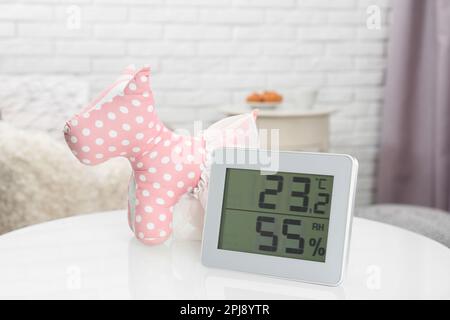 Digitales Hygrometer mit Thermometer auf dem Tisch im Kinderzimmer. Optimale Luftfeuchtigkeit für Kinder Stockfoto