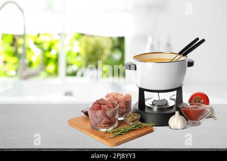 Zusammensetzung mit Fondue-Topf und Fleisch auf dem Tisch in der Küche. Platz für Text Stockfoto