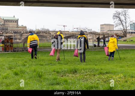Dresden, Deutschland. 01. April 2023. Vier Mitarbeiter der Deutschen Post AG gehen mit den roten Säcken der Stadt Dresden zur Reinigung der Elbwiesen auf die Wiese. Das Einsatzgebiet der erstreckt sich auf beiden Seiten der Elbe von Cossebaude bis Pillnitz und ist insgesamt 30 km lang. Kredit: Daniel Schäfer/dpa/Alamy Live News Stockfoto