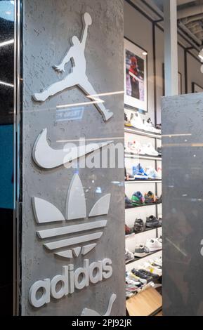 Air Jordan, Nike und Adidas Logos beliebter Schuh- und Bekleidungsmarken im Inneren eines Sportgeschäfts mit mehreren Marken. Minsk, Weißrussland, 2023 Stockfoto