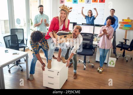 Eine junge Mitarbeiterin amüsiert sich mit ihren Kollegen in einer fröhlichen Atmosphäre im Büro. Mitarbeiter, Job, Büro Stockfoto