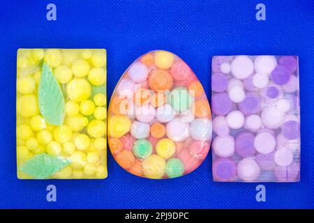 Drei durchsichtige Seifenstücke mit bunten Kugeln auf blauem Hintergrund. Stockfoto