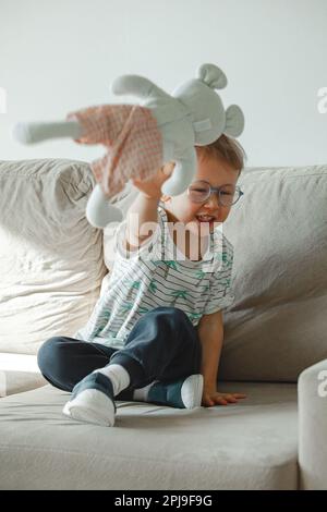 Ein Kind mit Autismus in einer Brille sitzt auf dem Sofa und traurig, wütend Stockfoto