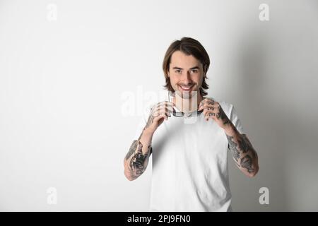 Junger Mann mit Tätowierungen auf Armen vor weißem Hintergrund Stockfoto