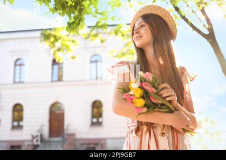 Hübsches Teenager-Mädchen mit einem Strauß Tulpen auf der Straße der Stadt. Platz für Text Stockfoto