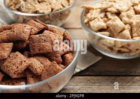 Verschiedene Frühstückszerealien in Glasschüsseln auf einem Holztisch, Nahaufnahme Stockfoto