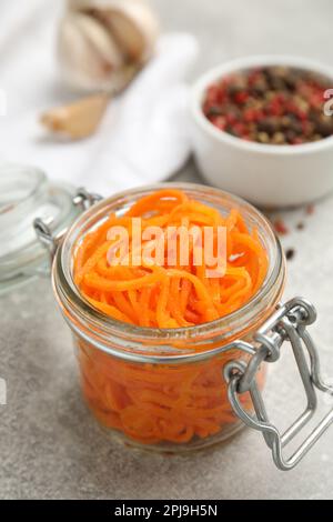 Köstlicher koreanischer Karottensalat im Glasgefäß auf einem grauen Tisch Stockfoto