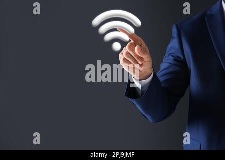 Mann, der das Wi-Fi-Symbol auf dem digitalen Bildschirm vor dunkelgrauem Hintergrund berührt, Nahaufnahme Stockfoto