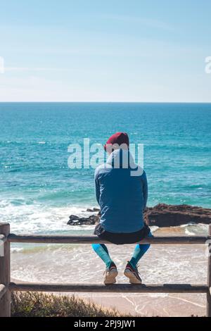 Touristen genießen die Aussicht von einem Aussichtspunkt auf einen Sandstrand an der Atlantikküste in der Nähe von Vila Nova de Milfontes, Odemira, Portugal. In den Fußfüßen folgen Stockfoto