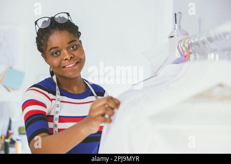 Portrait glückliche afrikanische, schwarze Schneiderin. Modedesignerin Bekleidung Kleidermacher lächelnd. Stockfoto