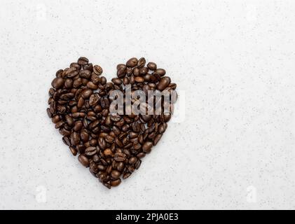 Konzept von Liebe oder Kaffee lieben. Herzform aus Kaffeebohnen auf einem Whiteboard. Stockfoto