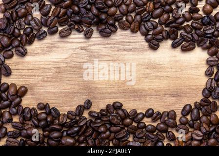 Geröstete Kaffeebohnen, die auf einem Holzbrett eine Einfassung bilden Stockfoto