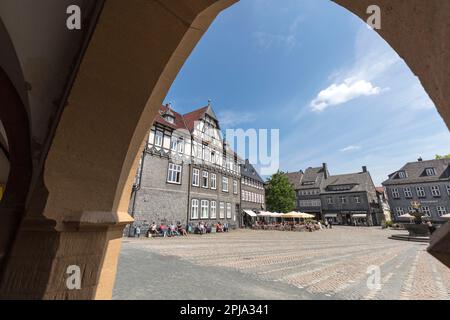 Historische, charmante mittelalterliche Gebäude, Geschäfte, Cafés und Restaurant auf dem Marktplatz durch den Rathausbogen, der zum UNESCO-Weltkulturerbe gehört, Goslar. Stockfoto