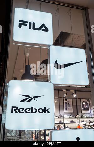 Reebok, Nike und Fila Logos beliebter Schuhe und Bekleidungsmarken im Inneren eines Sportgeschäfts mit mehreren Marken. Minsk, Weißrussland, 2023 Stockfoto