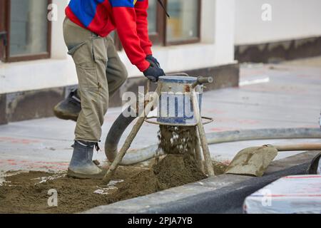 Installation von Zementbodenbodenbohlen mit Bewehrungsstahl. Maschinenboden-Einbaubohle. Stockfoto