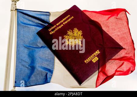 Ein französischer Pass liegt vor dem Hintergrund der blauen, weißen und roten Farben der französischen Flagge. Stockfoto
