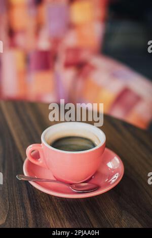 Rosa Tasse schwarzen Kaffee auf einem Tisch in einem Café. Selektiver Fokus. Platz für Text. Stockfoto