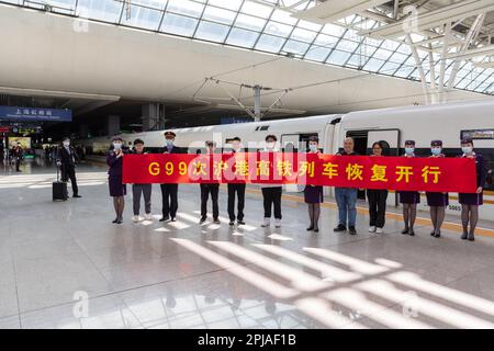 Schanghai. 1. April 2023. Passagiere posieren für ein Gruppenfoto mit den Besatzungsmitgliedern des Zuges G99 am Bahnhof Shanghai Hongqiao im Osten Chinas Shanghai, 1. April 2023. Als der Zug G99 den Bahnhof Shanghai Hongqiao zur Hong Kong West Kowloon Station verließ, wurde der Hochgeschwindigkeitszug Shanghai-Hong Kong am Samstag wieder aufgenommen. Kredit: Wang Xiang/Xinhua/Alamy Live News Stockfoto