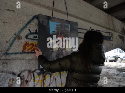 Irpin, Ukraine. 31. März 2023. Eine Frau hängt ein Gemälde auf einer Ausstellung, die der Befreiung Buchas gewidmet ist. Die Ukraine feiert den ersten Jahrestag des Beginns des größten militärischen Angriffs in Europa seit dem Zweiten Weltkrieg mit einer nichtoffiziellen Kunstausstellung mit Skulpturen, Gemälden, Und Fotos von verschiedenen lokalen Künstlern unter der zerstörten Romanov-Brücke zwischen Irpin und Kiew anlässlich des Jahrestages der Befreiung von Bucha. Kredit: SOPA Images Limited/Alamy Live News Stockfoto