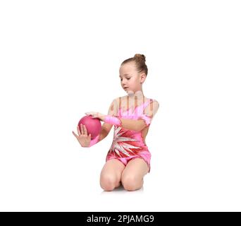 Kleine Mädchen-Turnerin in roten Kleidern posieren mit dem ball Stockfoto