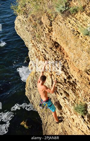 Männlicher Kletterer klettert auf eine Felswand Stockfoto