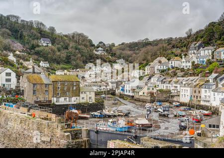 Von der Meeresschutzmauer im Hafen von Polperro mit Blick auf die festgemachten Boote bei Ebbe in Richtung der umhüllenden Dorfhütten. Stockfoto