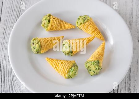 Tortilla-Chips, gefüllt mit Guacamole auf dem Teller Stockfoto