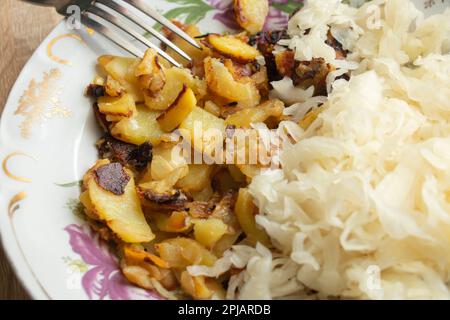 Gebratene Kartoffeln mit Kohl auf einem Teller auf dem Tisch Stockfoto