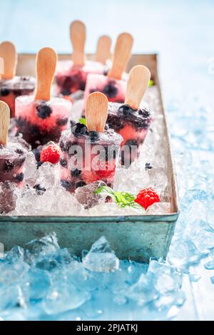 Köstliches und hausgemachtes Beereneis auf einem Stock. Gefrorene Waldfrüchte als Sorbeteis. Stockfoto