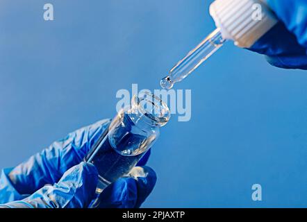 Hände eines Labortechnikers mit einem Röhrchen mit Blutprobe, der Laborassistent hält ein Blutteströhrchen für die Forschung. Die Entnahme von biologischem Material zur Identifizierung Stockfoto