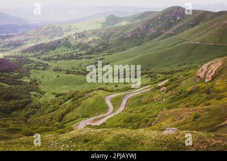 Gefährliche, gewundene M-20 Schotterstraße zum Tskhratskaro Pass, Georgia, mit Auto in der Ferne und Trialeti (Kaukasus) Berglandschaft. Stockfoto