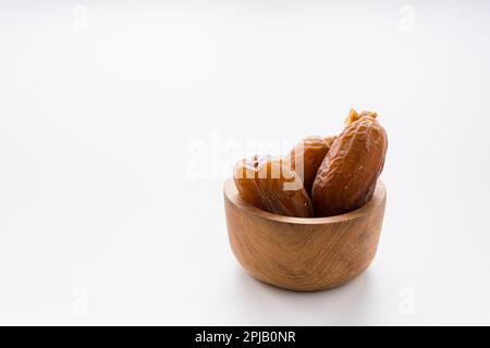 Getrocknete Dattelfrüchte in Holzschüssel auf weißem Hintergrund isoliert. Stockfoto