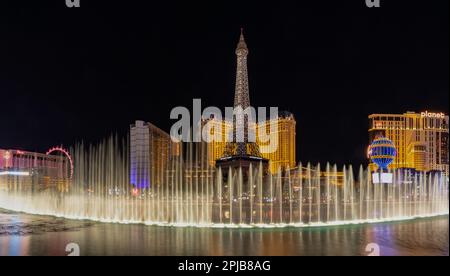 Ein Bild der Bellagio Fountain Water Show bei Nacht, mit dem Eiffelturm des Paris Las Vegas dahinter. Stockfoto