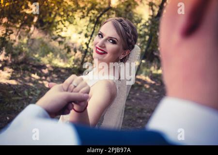 Frisch verheiratetes Paar, das zärtliche Momente hat, Händchen hält Stockfoto