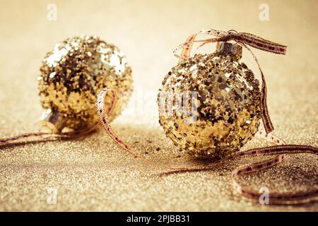 Goldene weihnachtsbälle auf glitzerndem Hintergrund mit Kopierbereich. Glitzernder Hintergrund Stockfoto