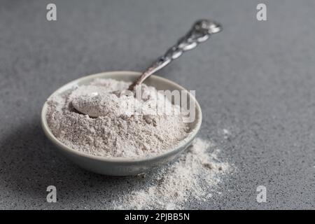Glutenfreies Buchweizenmehl zum Backen in der Schüssel auf grauem Hintergrund Stockfoto