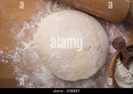 Hausgemachter Hefeteig, frisch zubereitet für Pizza oder Brot auf Holzhintergrund. Hausmannskost-Konzept Stockfoto