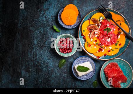 Gesunder Wintersalat - Persimmon Carpaccio Salat mit Granatapfel, Feta, rosa Grapefruit und Feigen Stockfoto