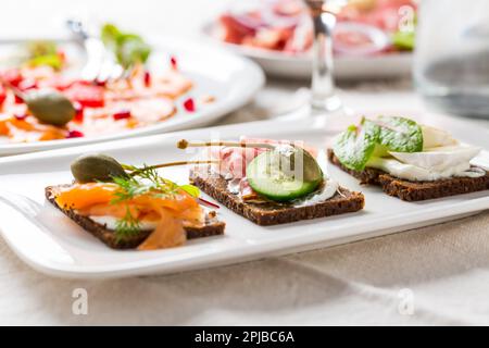 Variation von gesunden offenen Sandwiches auf Pumpernickel Brot mit Gemüse, Lachs, Schinken und Vorspeisen mit Rotwein Stockfoto