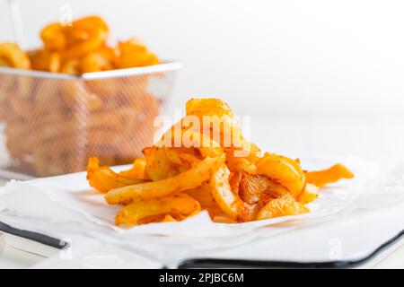 Würzige gewürzte lockige Pommes Frites. Bereit, auf weißem Hintergrund zu essen Stockfoto