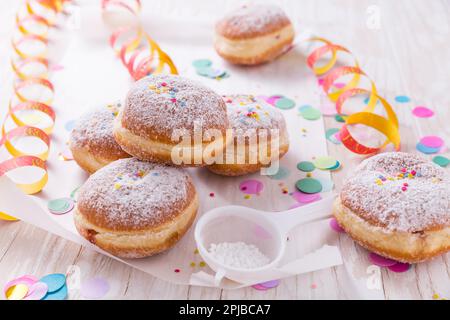 Traditioneller Berliner für Fasching und Party. Deutsch Krapfen oder Donuts mit Streamer und Konfetti. Bunte Karneval oder Geburtstag Bild Stockfoto