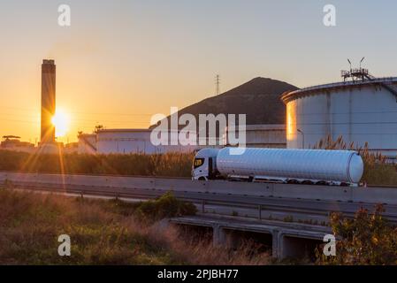 Zisternwagen für den Transport kryogener gefährlicher Gase, die auf einer Straße mit großen Ablagerungen einer Raffinerie zirkulieren. Stockfoto