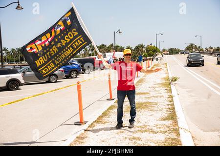 Palm Beach, Florida, USA - 1. April 2023: Junger Mann mit der Flagge in der Nähe der Mar-a-Lago Residenz von Donald Trump und zeigt seine Unterstützung Stockfoto