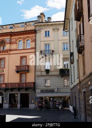 Pastellfarbene Gebäude mit Balkonen über einem Tabacchi Shop in der Stadt Aosta, Aosta Valley, Italien Stockfoto