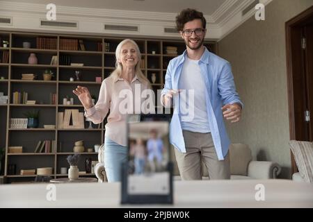 Fröhliche, fröhliche Seniorin und Blogger, die zu Hause tanzen Stockfoto