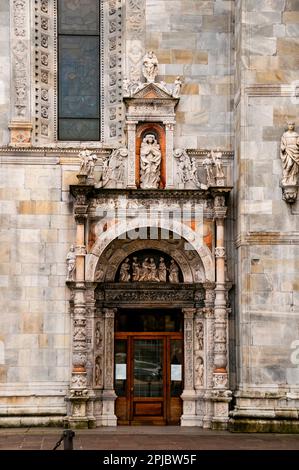 Duomo di Como mit einer Ädikule, die von zwei Schriftrollen getragen wird, bekannt als La Porta della Rana-Door of the Frog, Italien. Stockfoto