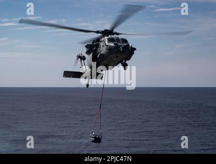 Ein MH-60s Knighthawk, angeschlossen an die "Tridents" des Helicopter Sea Combat Squadron (HSC) 9, transportiert Munition während einer Ladung mit USNS Medgar Evers (T-AKE 13), 31. März 2023. Ford führt im Atlantik Routineeinsätze und Schulungen durch, um die Einsatzbereitschaft aufrechtzuerhalten. Als erstklassiges Schiff von Ford-Flugzeugträgern stellt CVN 78 einen Generationssprung in den USA dar Die Fähigkeit der Navy, Energie auf globaler Ebene zu projizieren. (USA Marinefoto von Mass Communication Specialist 2. Class Nolan Pennington) Stockfoto