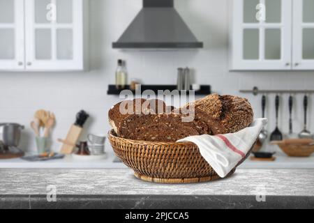 Frisches Roggenbrot in Korb auf grauem Tisch in der Küche Stockfoto